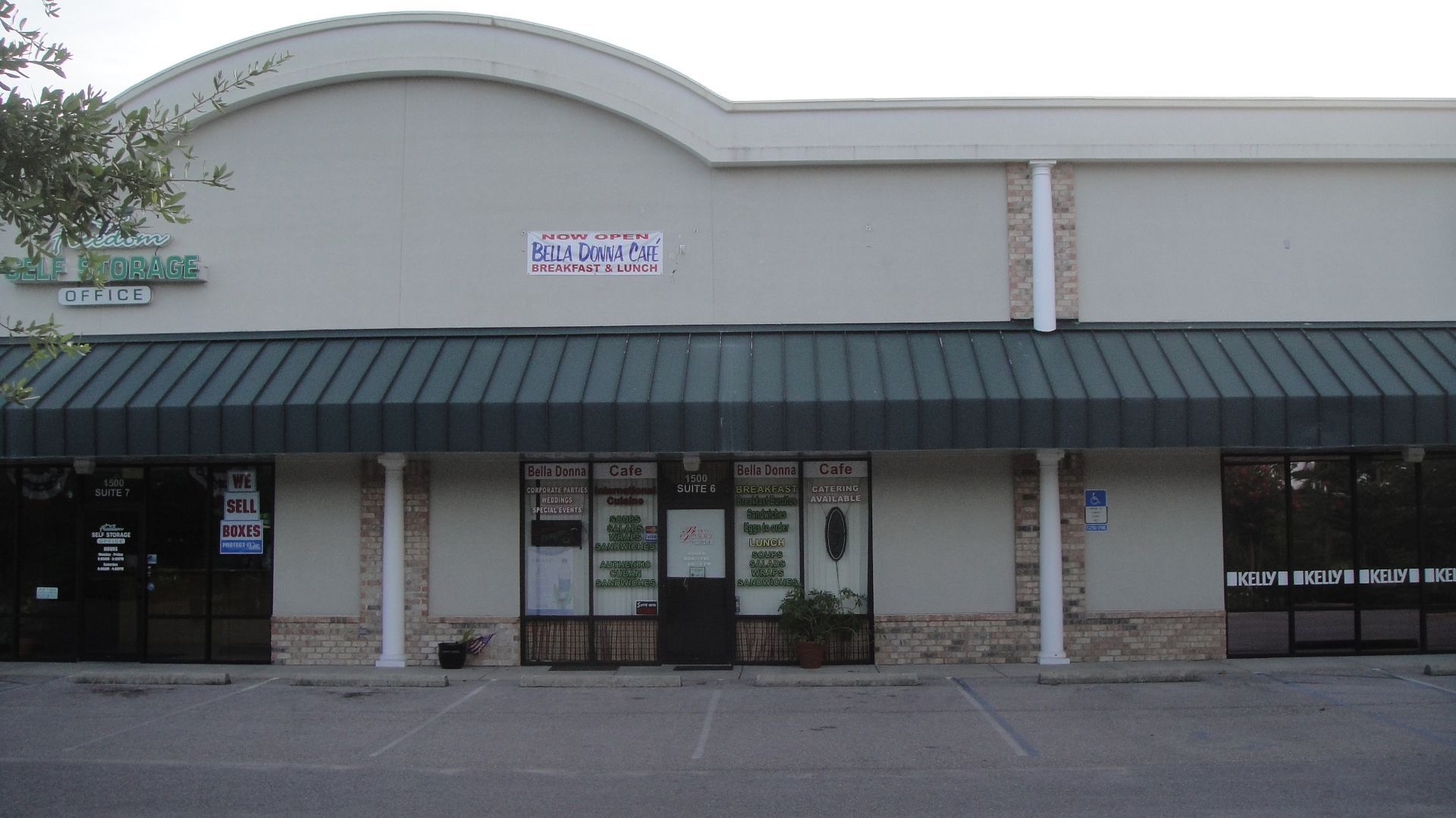 Strip-mall storefront with dark awning, glass doors, and a curved beige facade