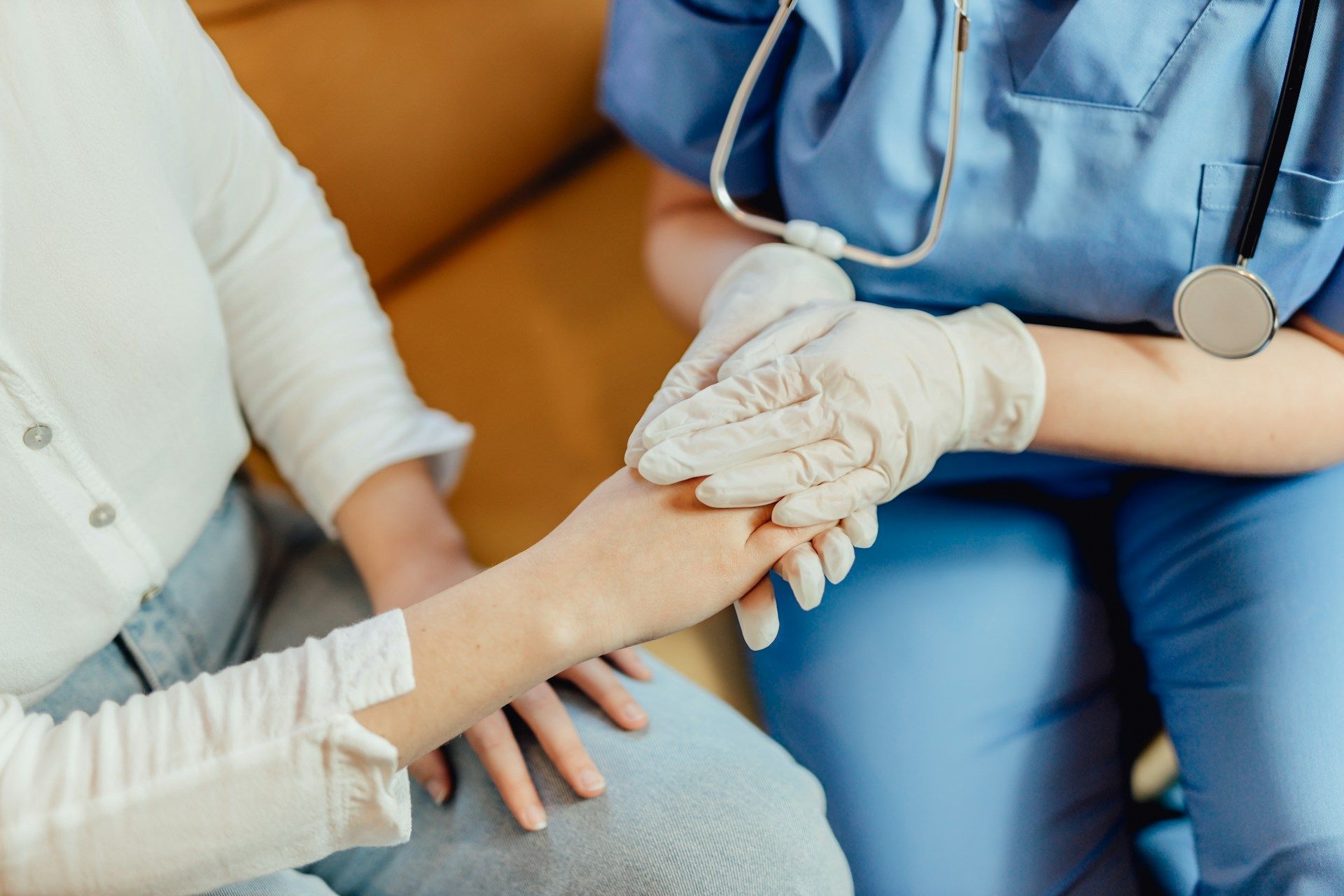 Healthcare worker holding a patient’s hand during a medical exam
