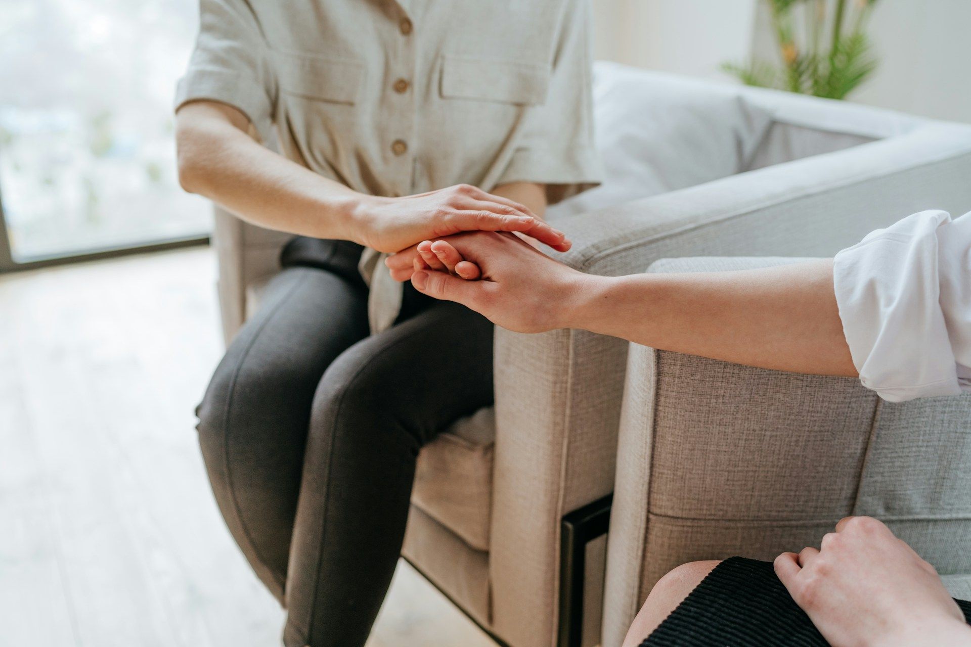 Two people holding hands in a chair during a comforting conversation