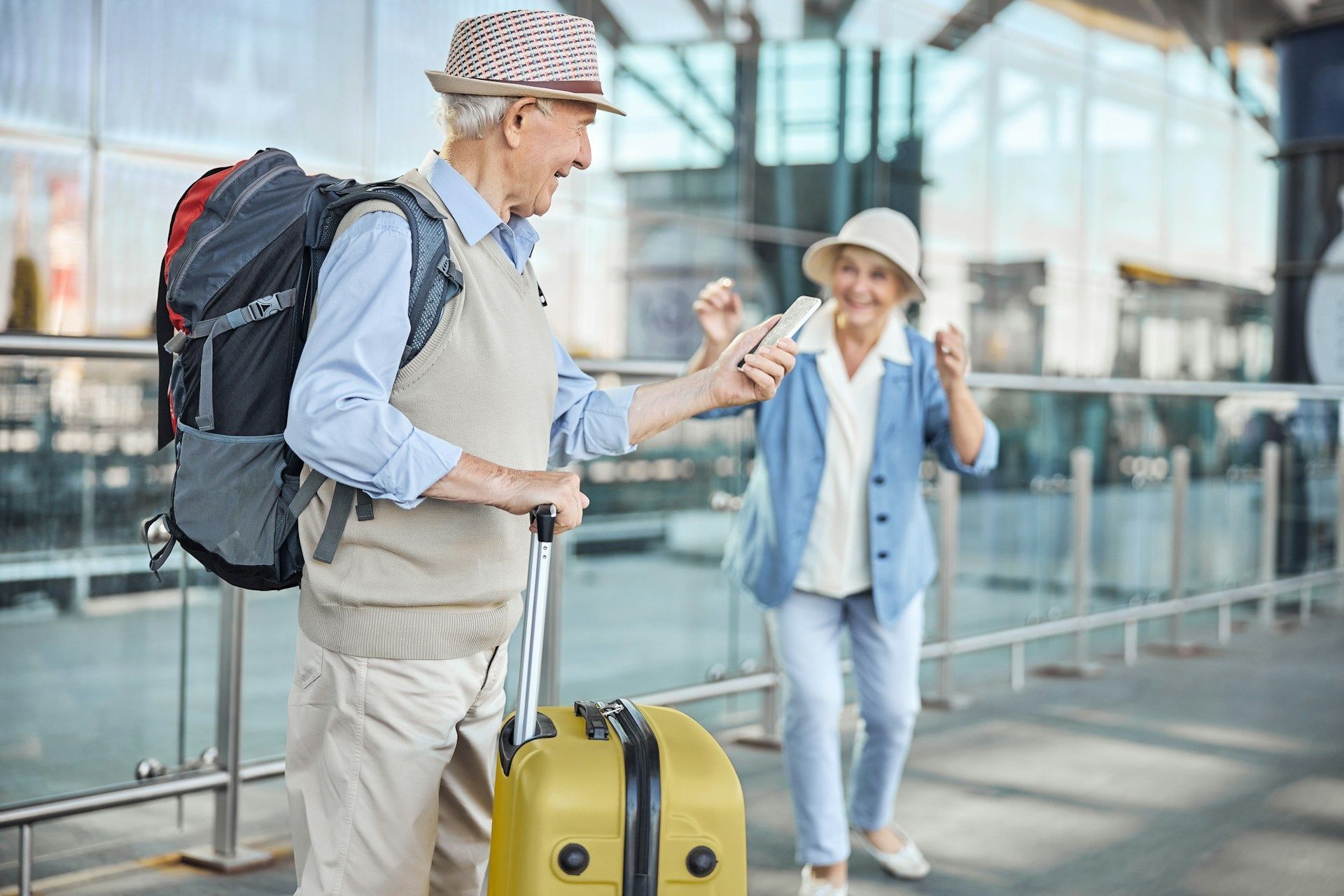 Traveler with backpack and rolling suitcase greets a person outside an airport terminal
