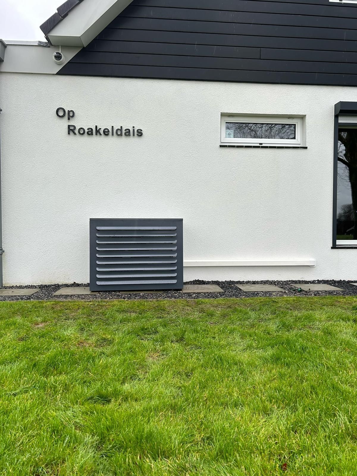 Wit stucwerkgebouw met zwart dak; tekst 