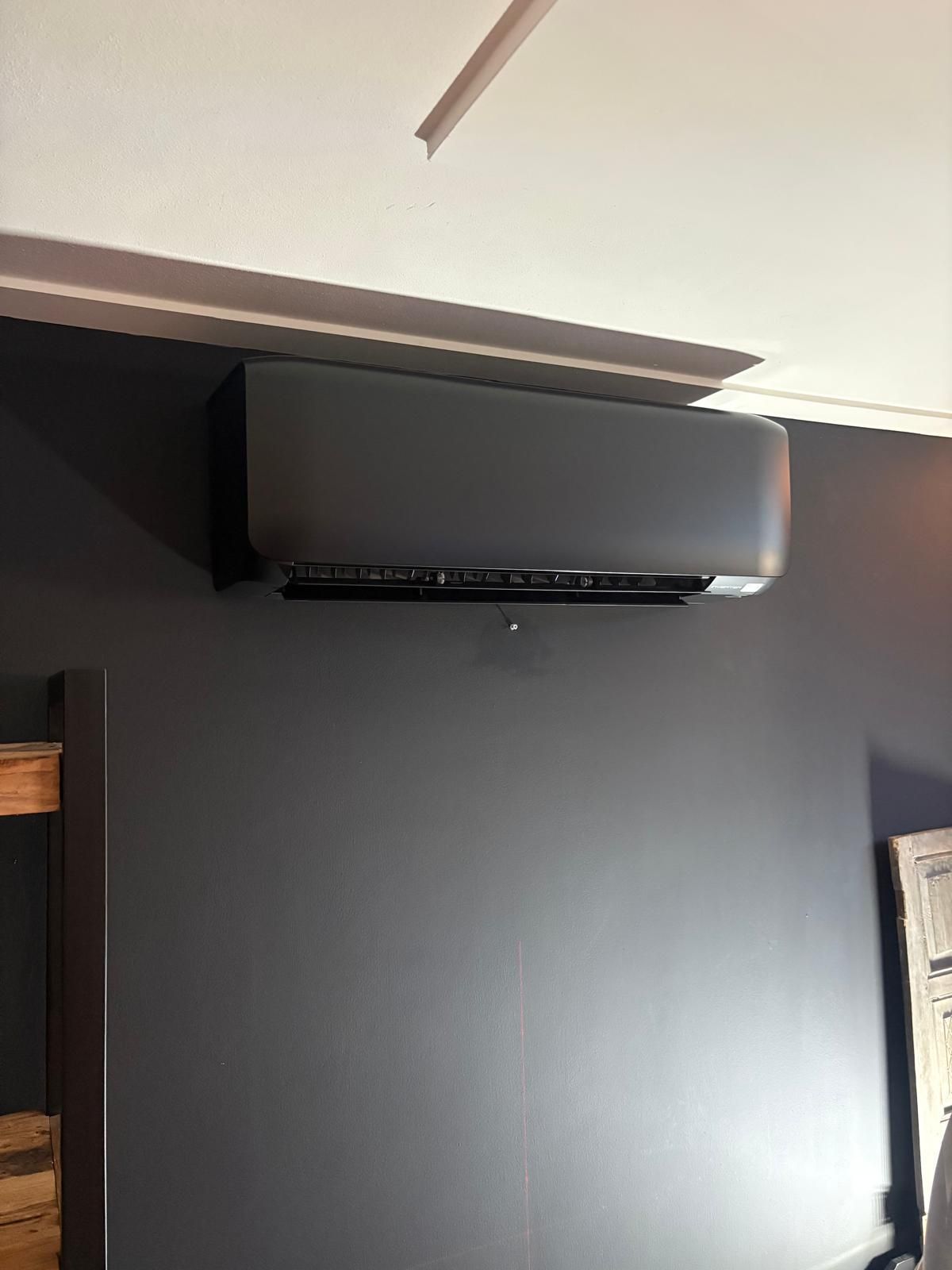 Donkergrijze wandairco op een donkergrijze muur, vlakbij een wit plafond.