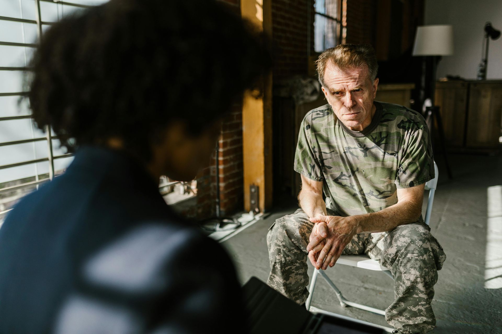 A man in a military uniform is sitting in a chair talking to a woman.
