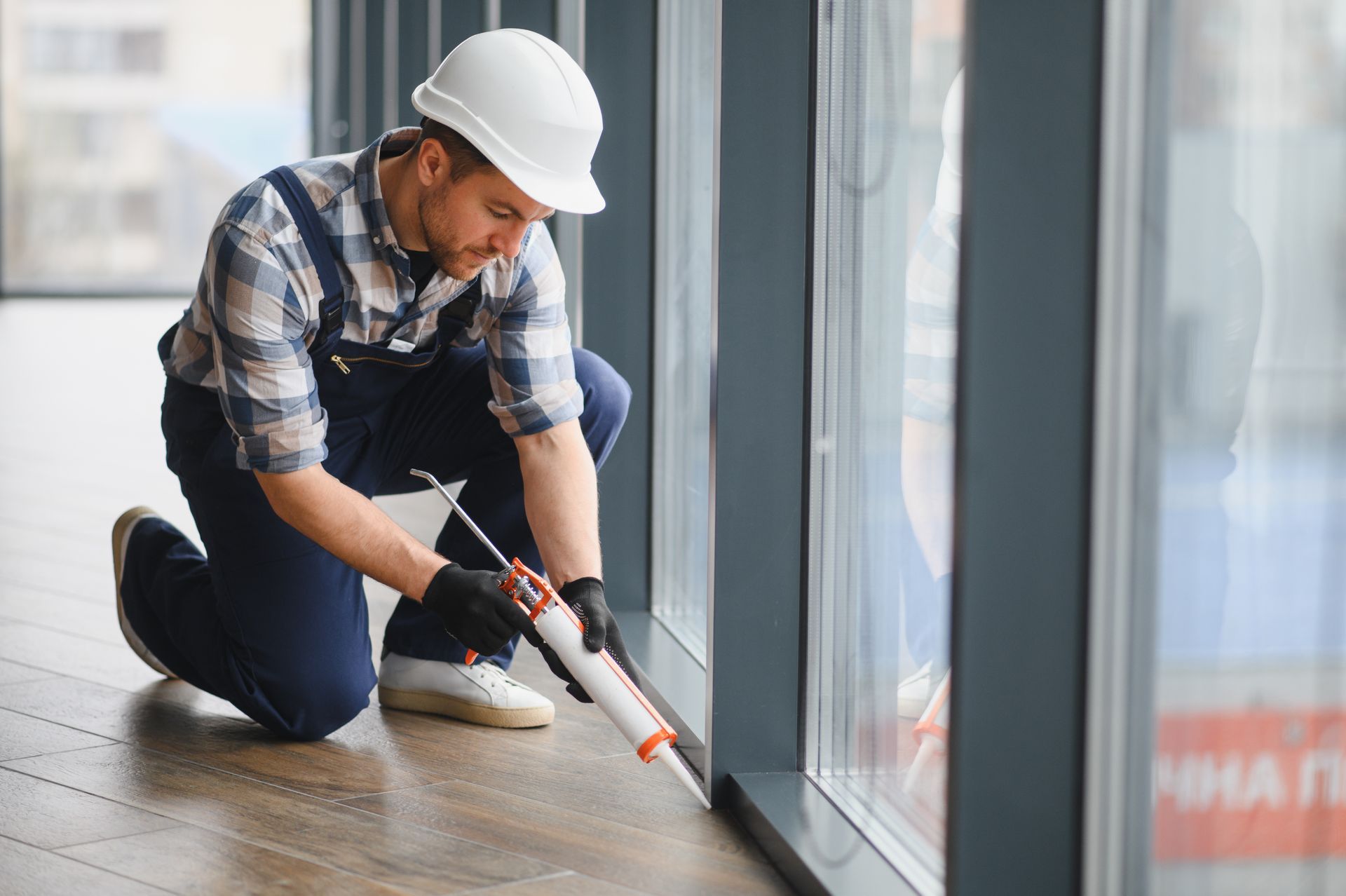 Worker applying sealant along a window frame for window waterproofing