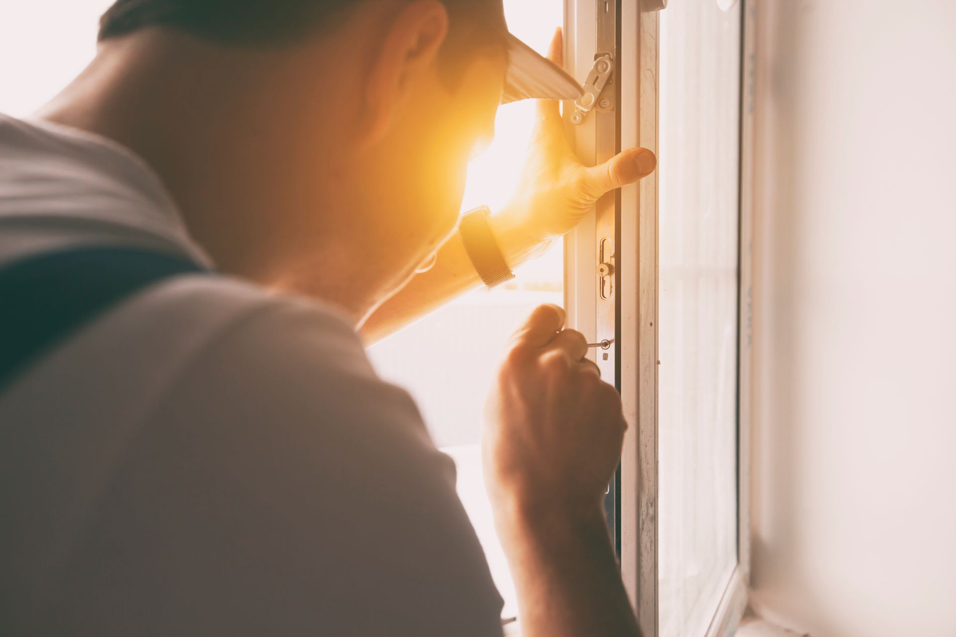 Technician adjusting a window latch during window replacement in a home