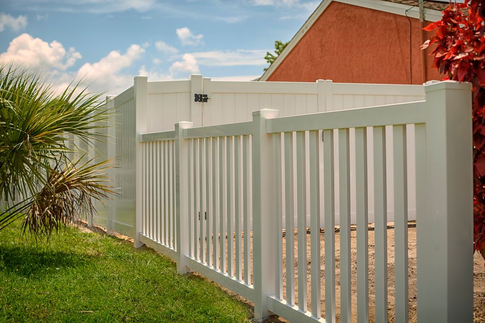 A Wooden Fence Is Surrounded By Palm Trees And Yellow Flowers — CQ Fencing & Retaining Walls In Clinton, QLD