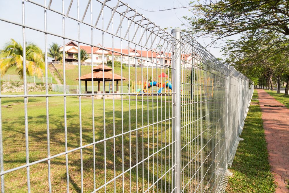 Wire Fence Along a Grassy Area with A Playground, Walkway, and Trees — CQ Fencing & Retaining Walls In Rockhampton, QLD