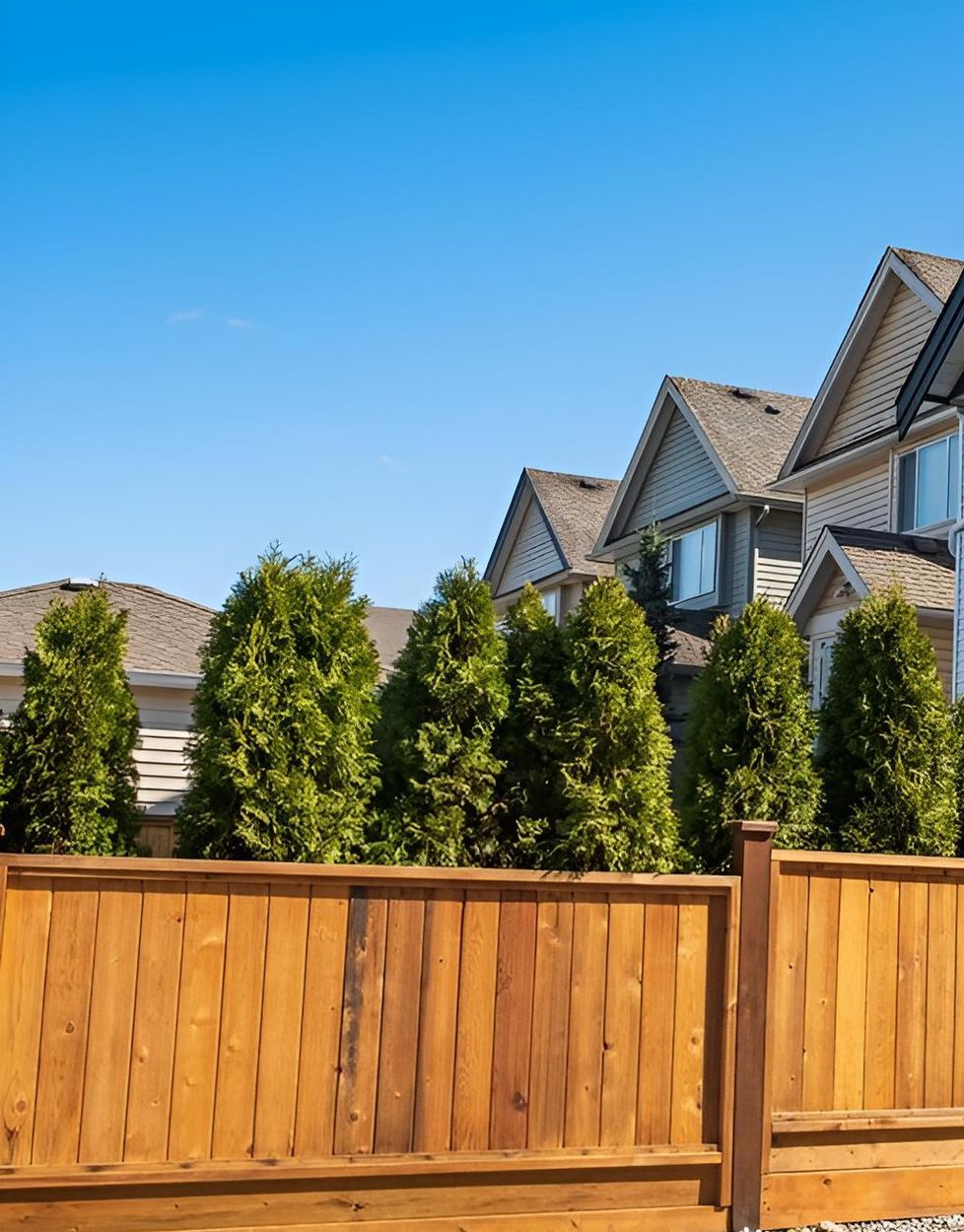 A White Picket Fence Surrounds A Lush Green Lawn In Front Of A House — CQ Fencing & Retaining Walls In Calliope, QLD