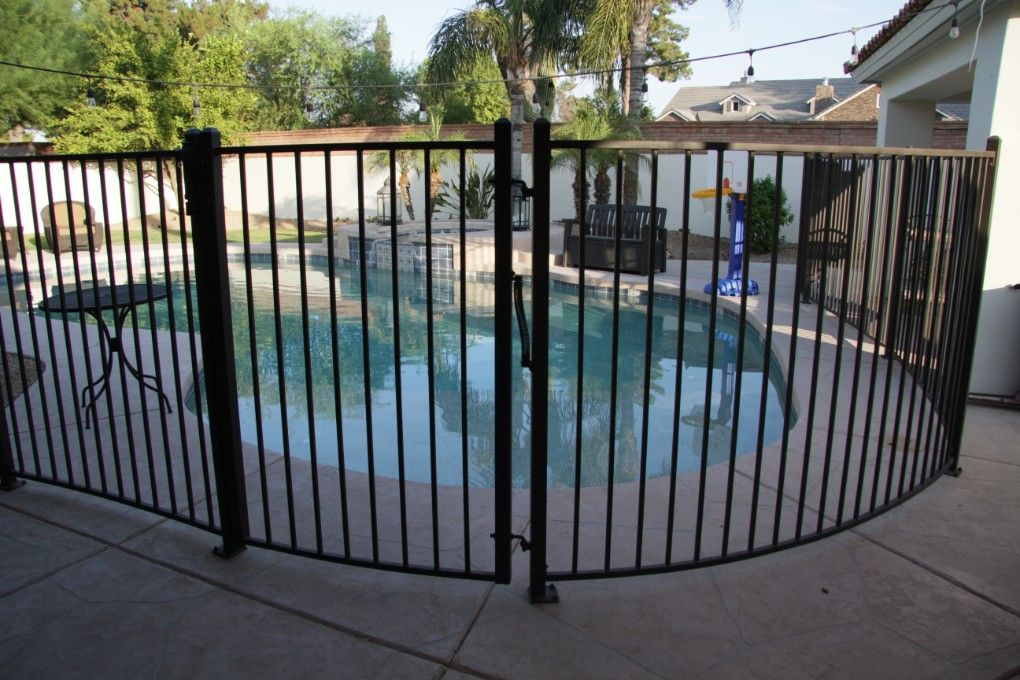A Wrought Iron Fence Surrounds A Large Swimming Pool — CQ Fencing & Retaining Walls In Biloela, QLD