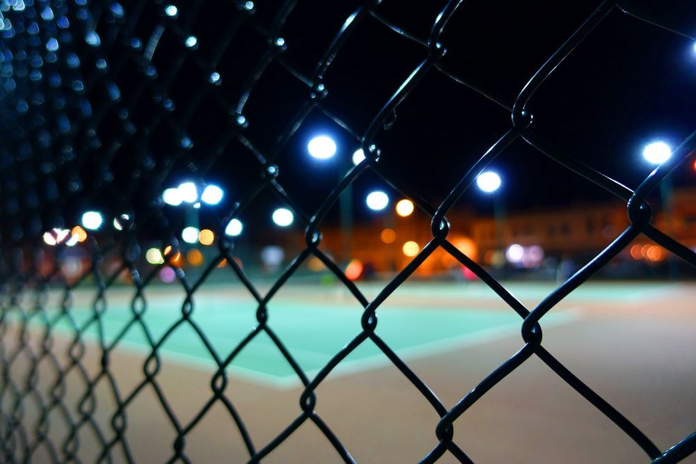 A Barbed Wire Fence Surrounds A Curvy Road — CQ Fencing & Retaining Walls In Clinton, QLD