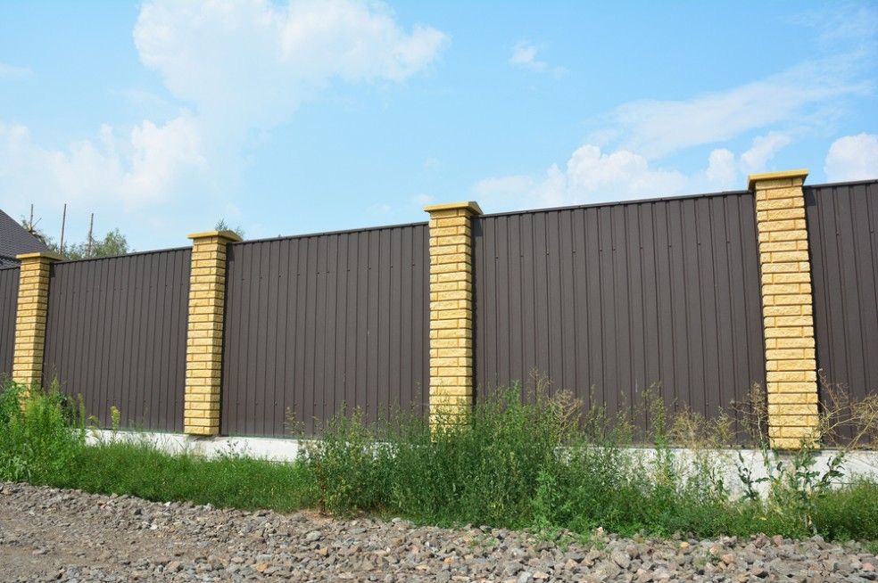A Brown Fence With Yellow Brick Pillars Is Surrounded By Grass — CQ Fencing & Retaining Walls In Yeppoon, QLD