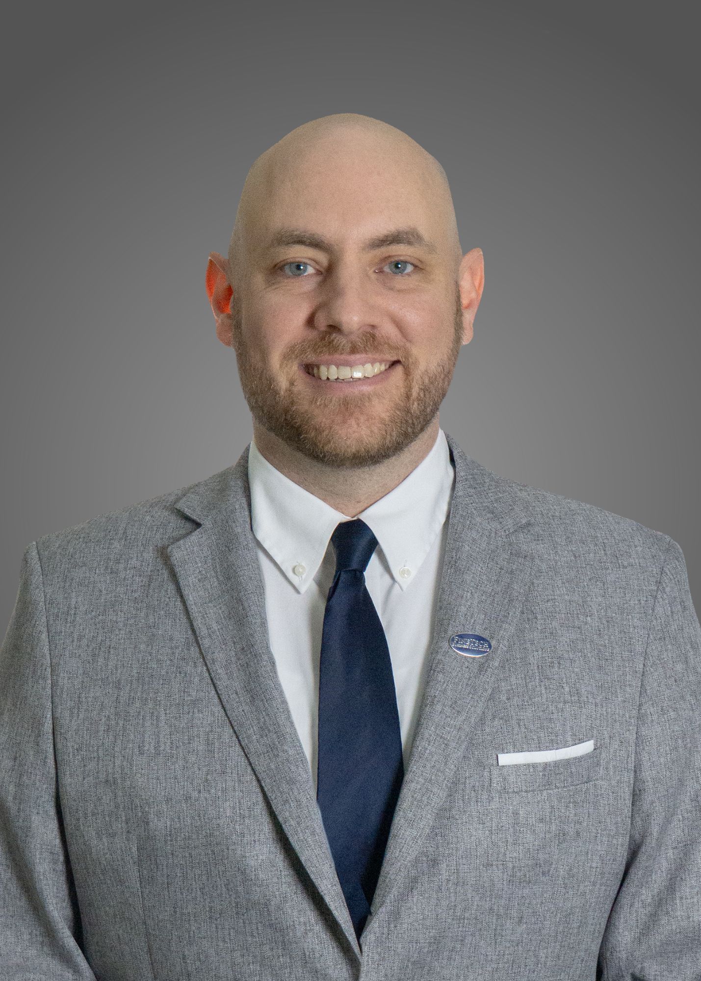A man with a beard and blue eyes in a grey suit