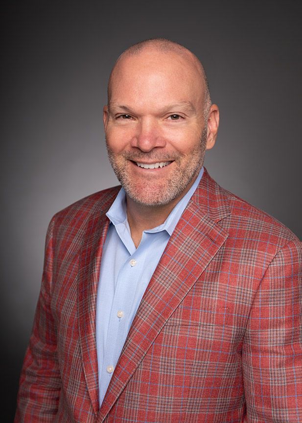 A man with short, styled hair in a light blue suit