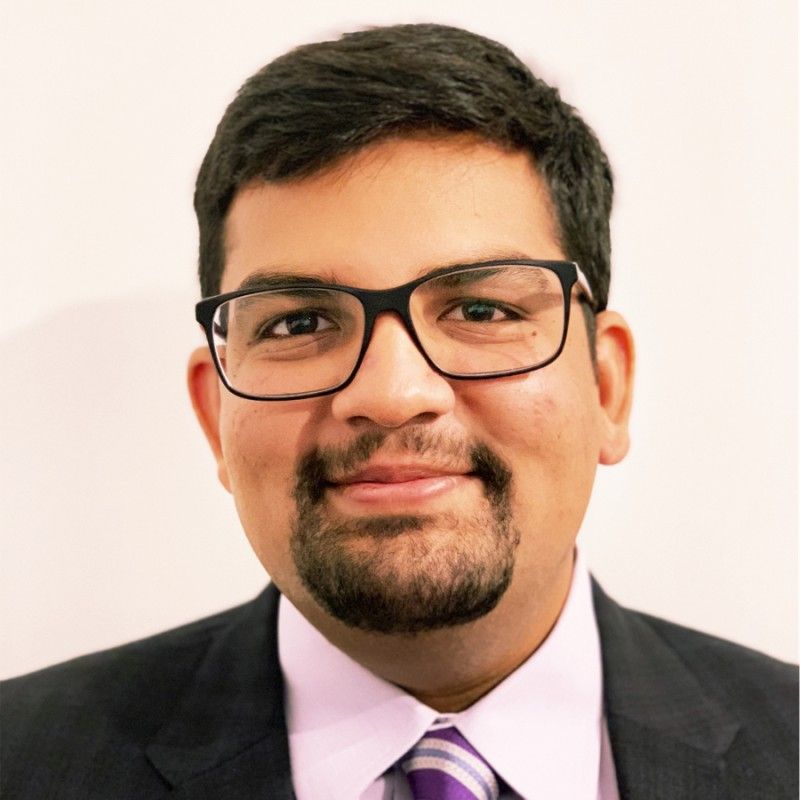 A man with dark hair, glasses, and a goatee