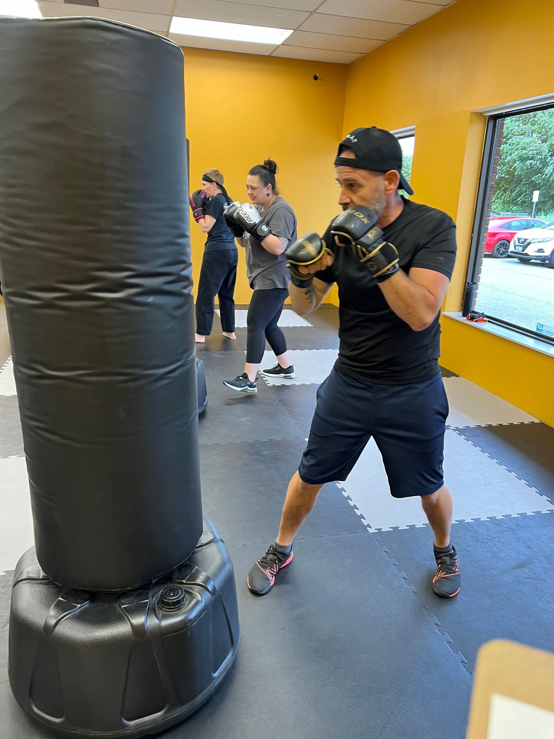 ELMA member training on a heavy bag near a window