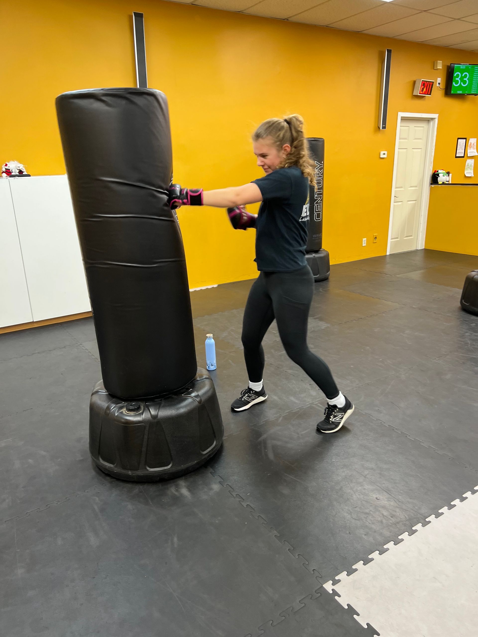 ELMA Fitness Kickboxing member kicking a heavy bag during class