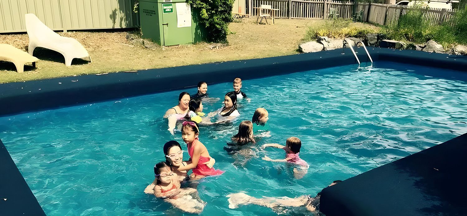 Family Swimming In A Blue Outdoor Pool