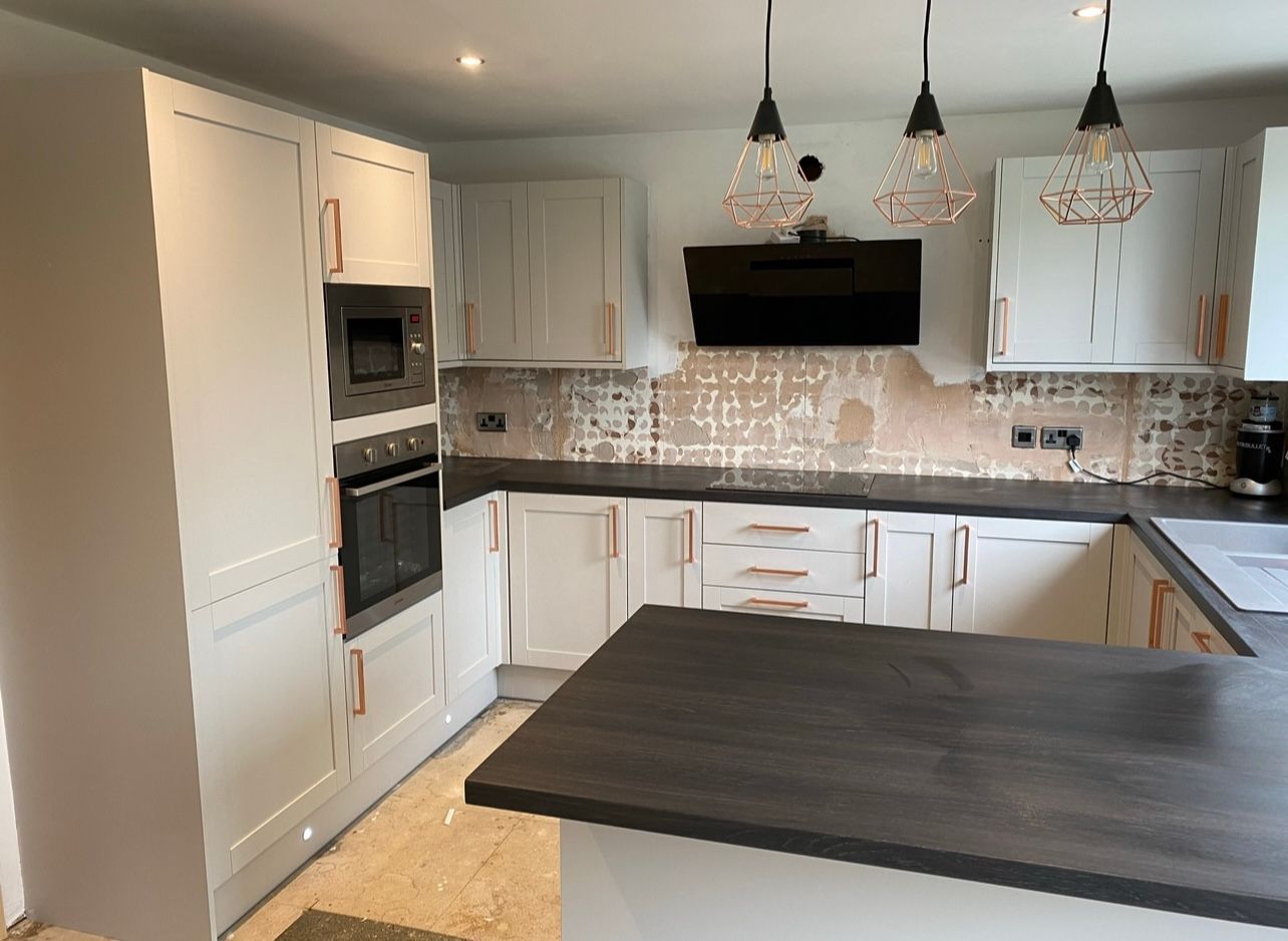 Modern kitchen with white cabinets, dark countertops, and a central island under pendant lights