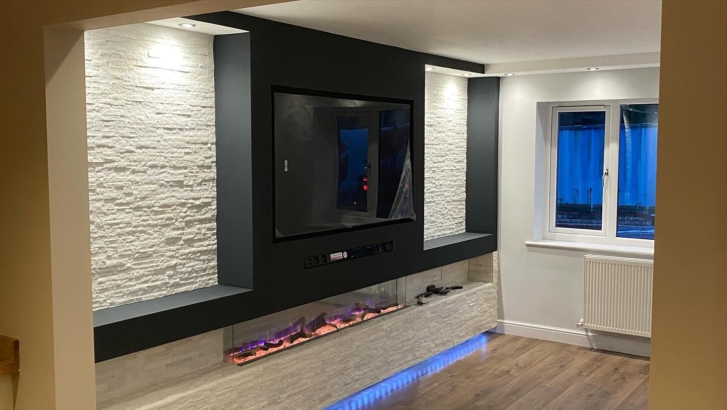 Modern living room with black accent wall, wall-mounted TV, lit stone panels, and window seating