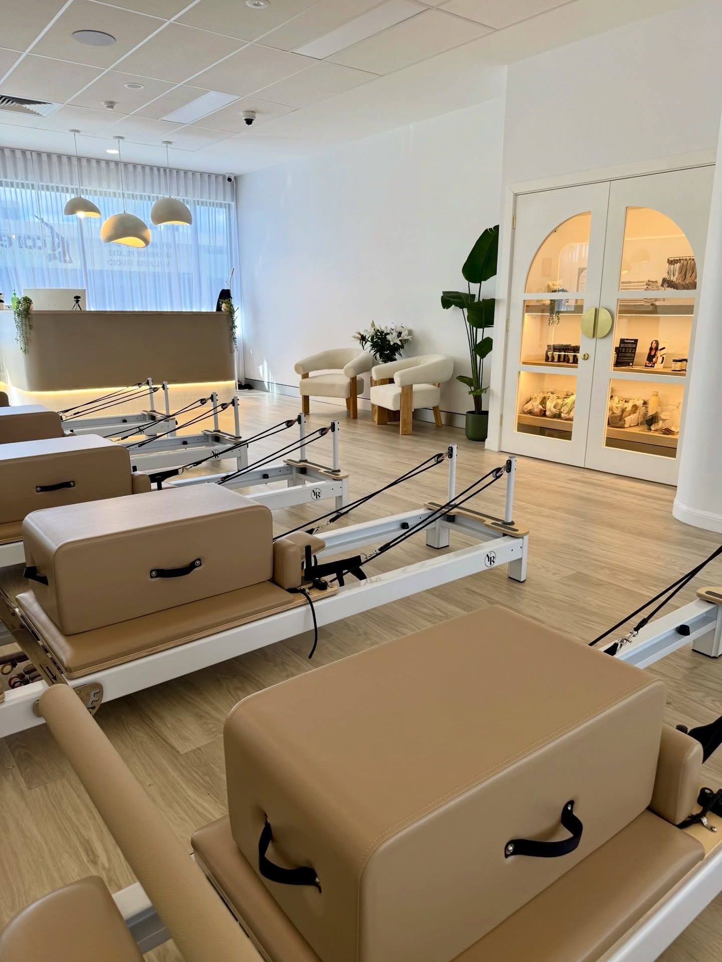 Bright Pilates studio with reformers, mirrors, and a clean beige and white interior