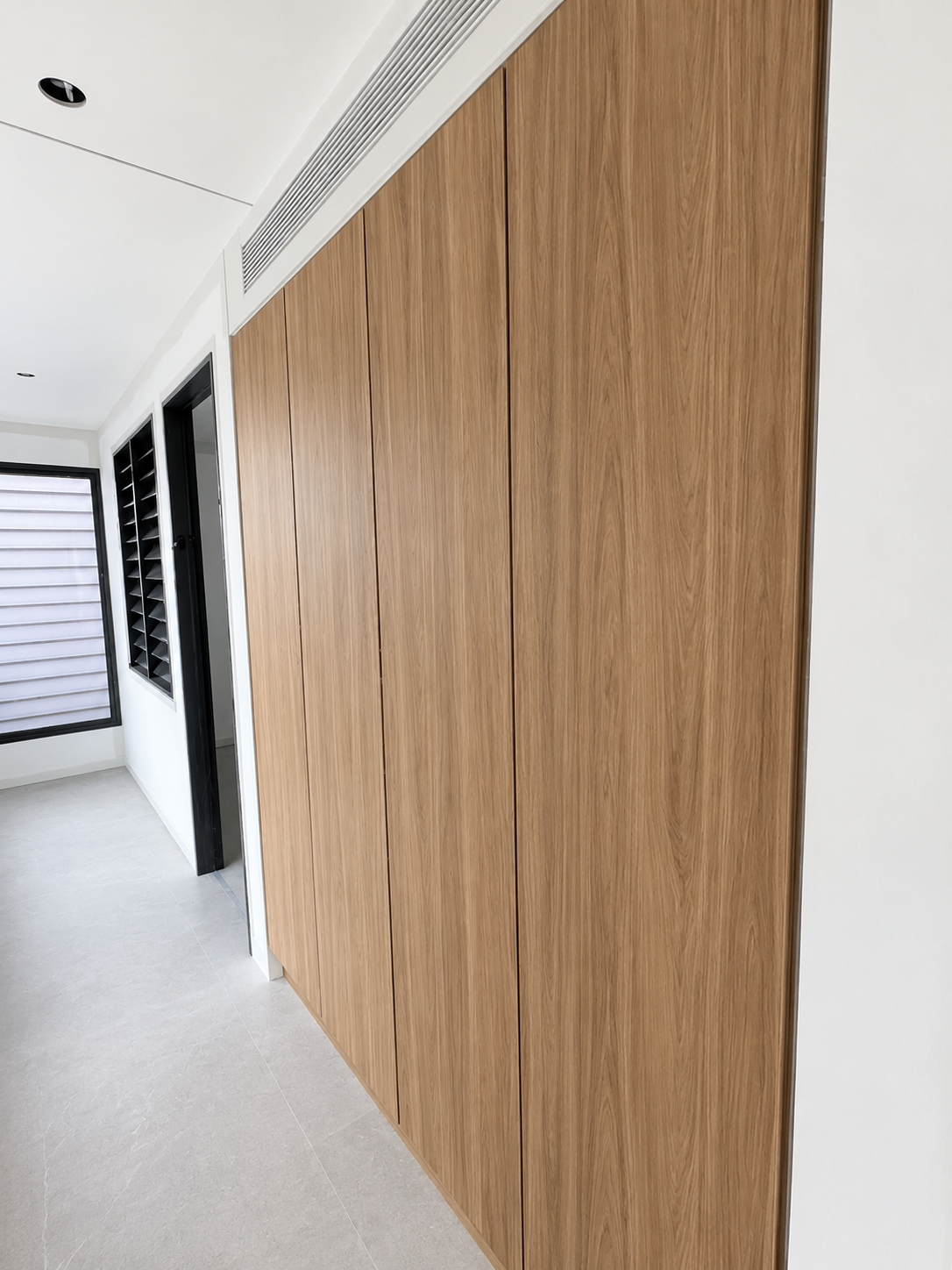 Modern hallway with tall wood-paneled sliding doors and light gray flooring