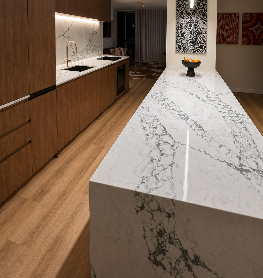 Modern kitchen with long white marble island, wood cabinetry, and a vase centerpiece