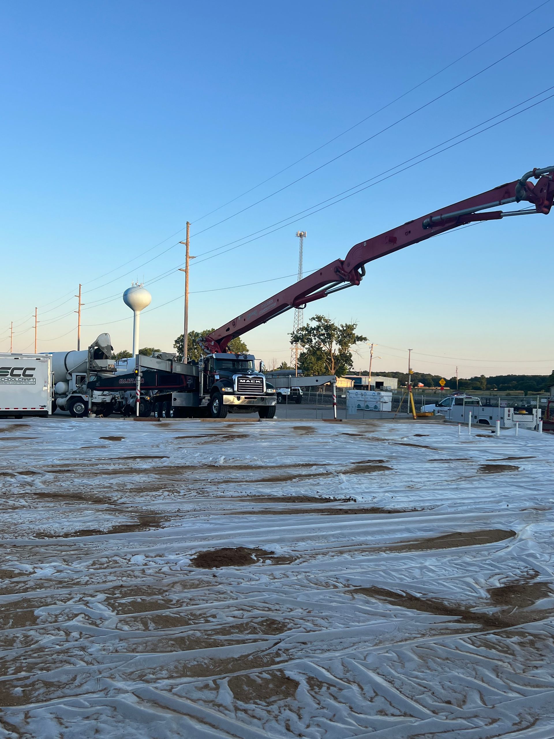 Concrete pump truck pouring at a snowy outdoor construction site under a clear blue sky