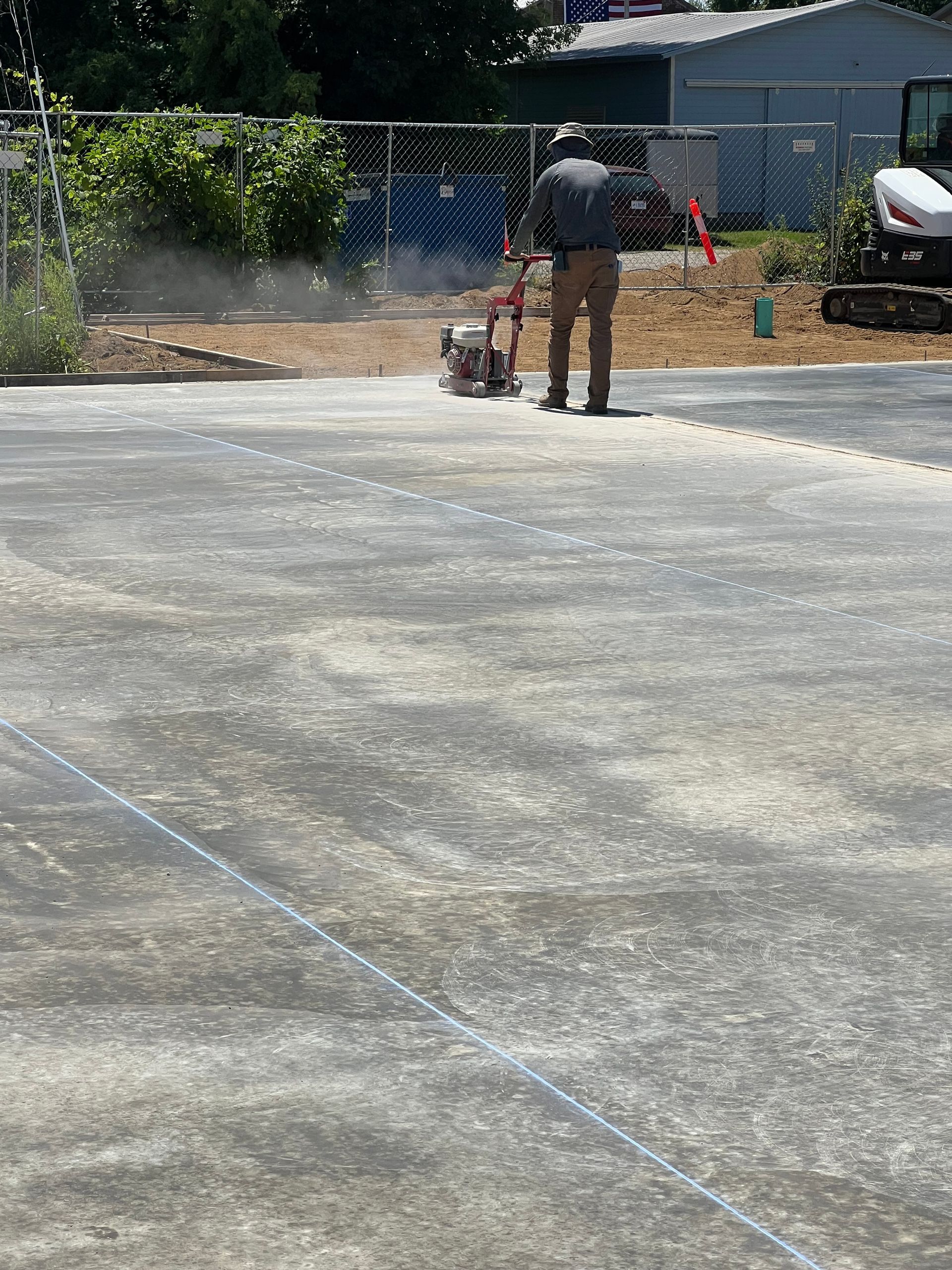 Driveway with gray pavers, white gravel strip, small green shrubs, and a short light post near a garage