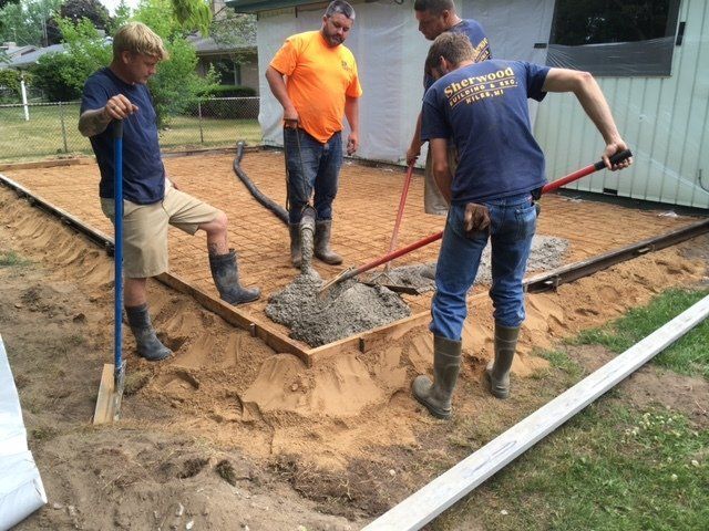 Workers pouring concrete into a foundation frame outdoors