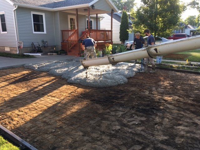 Construction workers pouring concrete driveway in front of a house