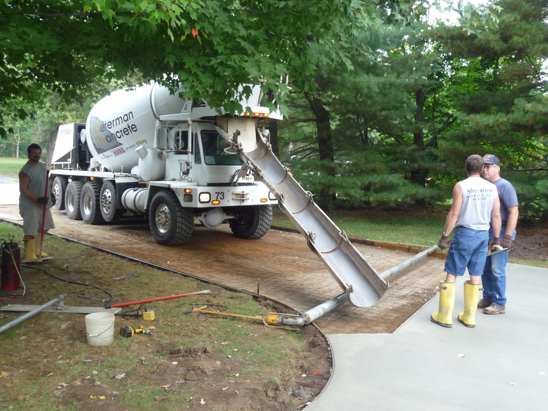 Driveway with gray pavers, white gravel strip, small green shrubs, and a short light post near a garage