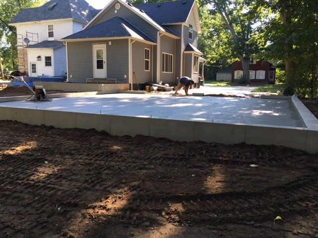 Driveway with gray pavers, white gravel strip, small green shrubs, and a short light post near a garage