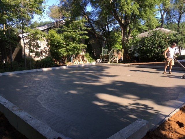 Outdoor skate ramp in a wooded park, with two skaters on the right side.