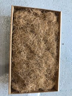 A cardboard box filled with shredded paper is sitting on a concrete surface.