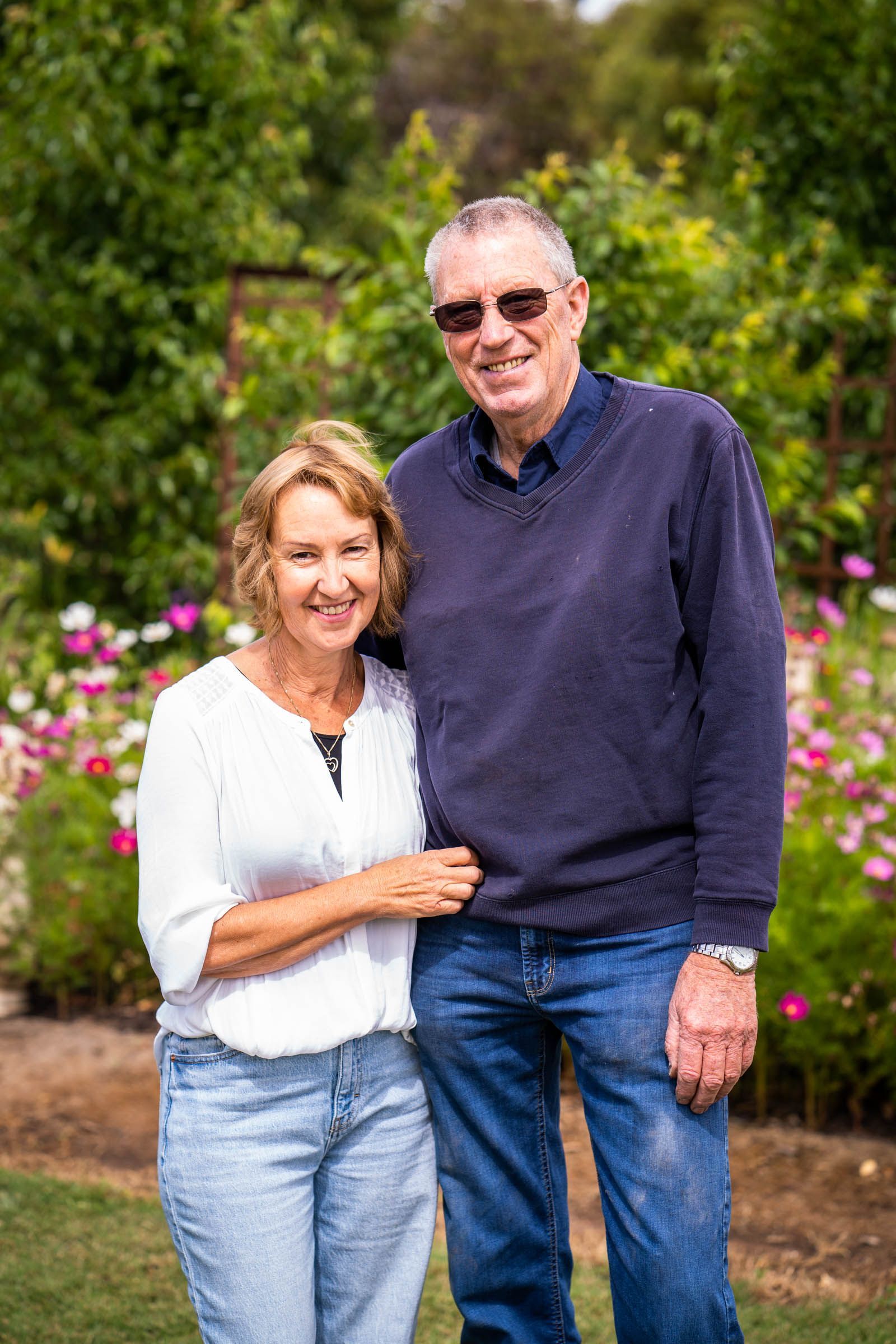 A man and a woman are posing for a picture in a garden.