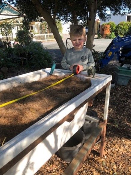 A young boy is measuring something with a tape measure