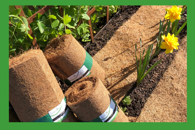 A row of rolls of soil in a garden with flowers in the background.