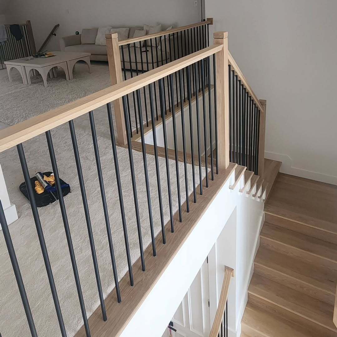 Stair landing with black cable railing, light wood trim, and gray carpet in a modern home