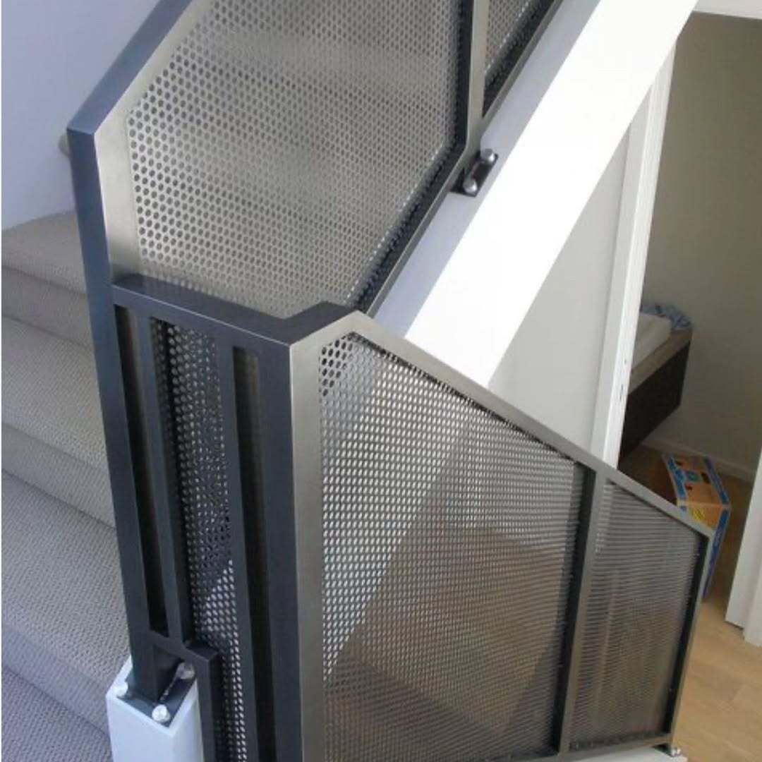 Metal staircase with perforated black railings and white support beam in an indoor setting