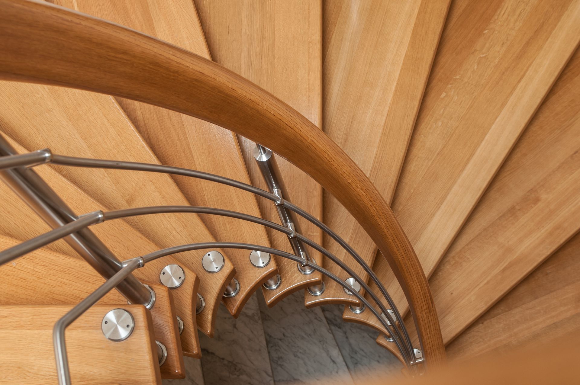 Curved wooden spiral staircase with metal railings and steps viewed from above