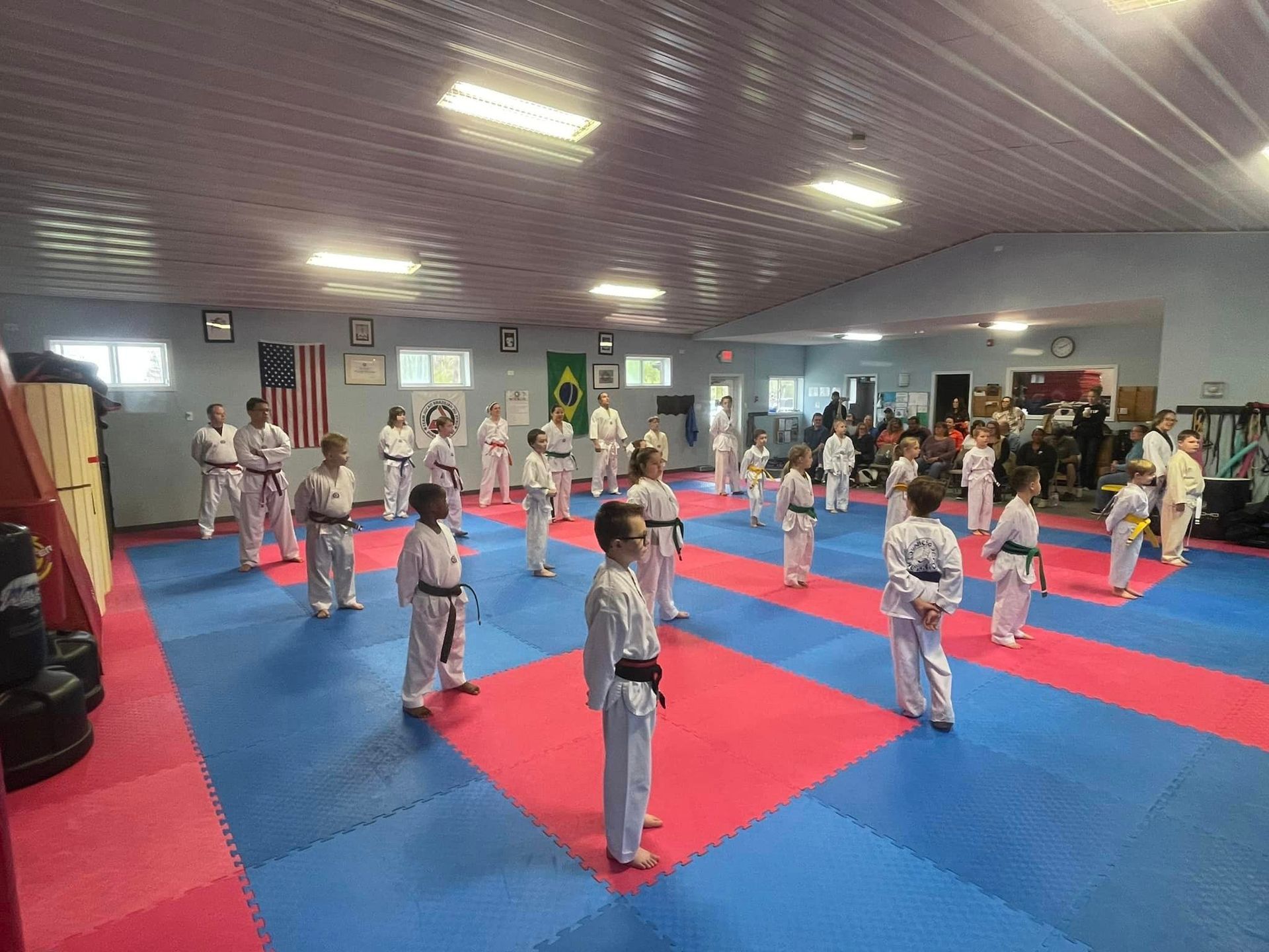 A group of children are practicing martial arts in a gym.