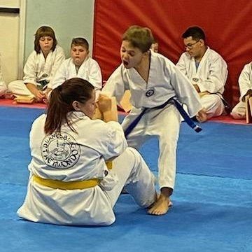 A group of people are practicing martial arts on a blue mat.
