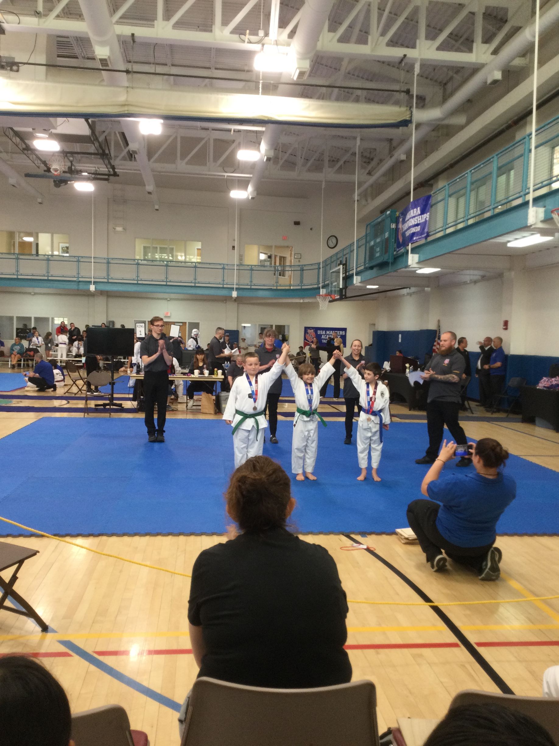 A group of kids are standing on a blue mat in a gym