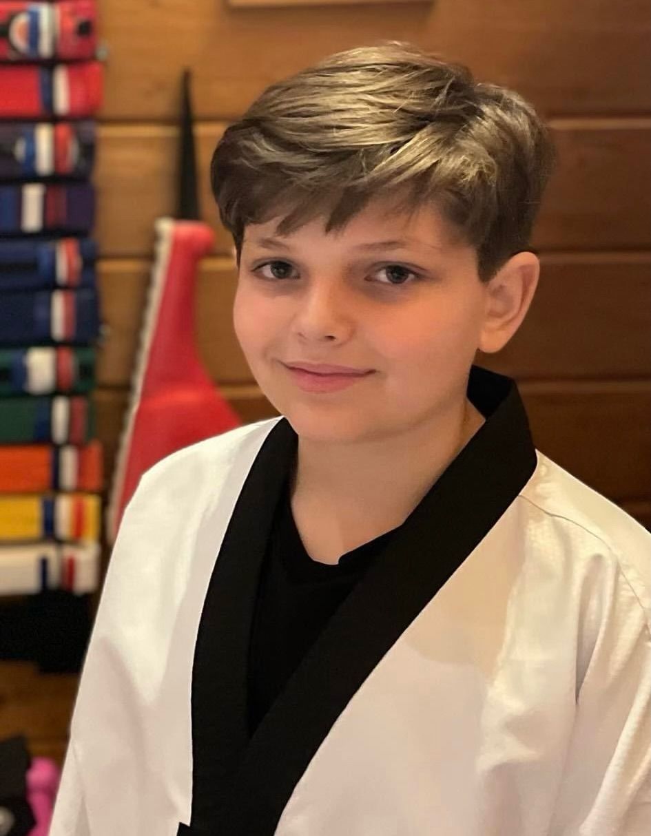A young boy wearing a white karate uniform and a black belt