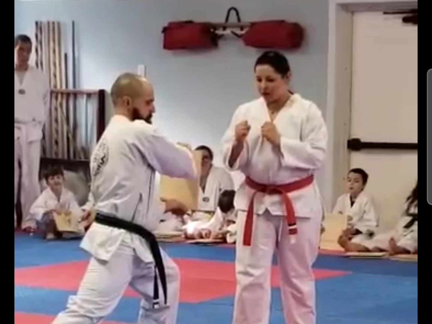 A man and a woman are practicing martial arts in a gym.