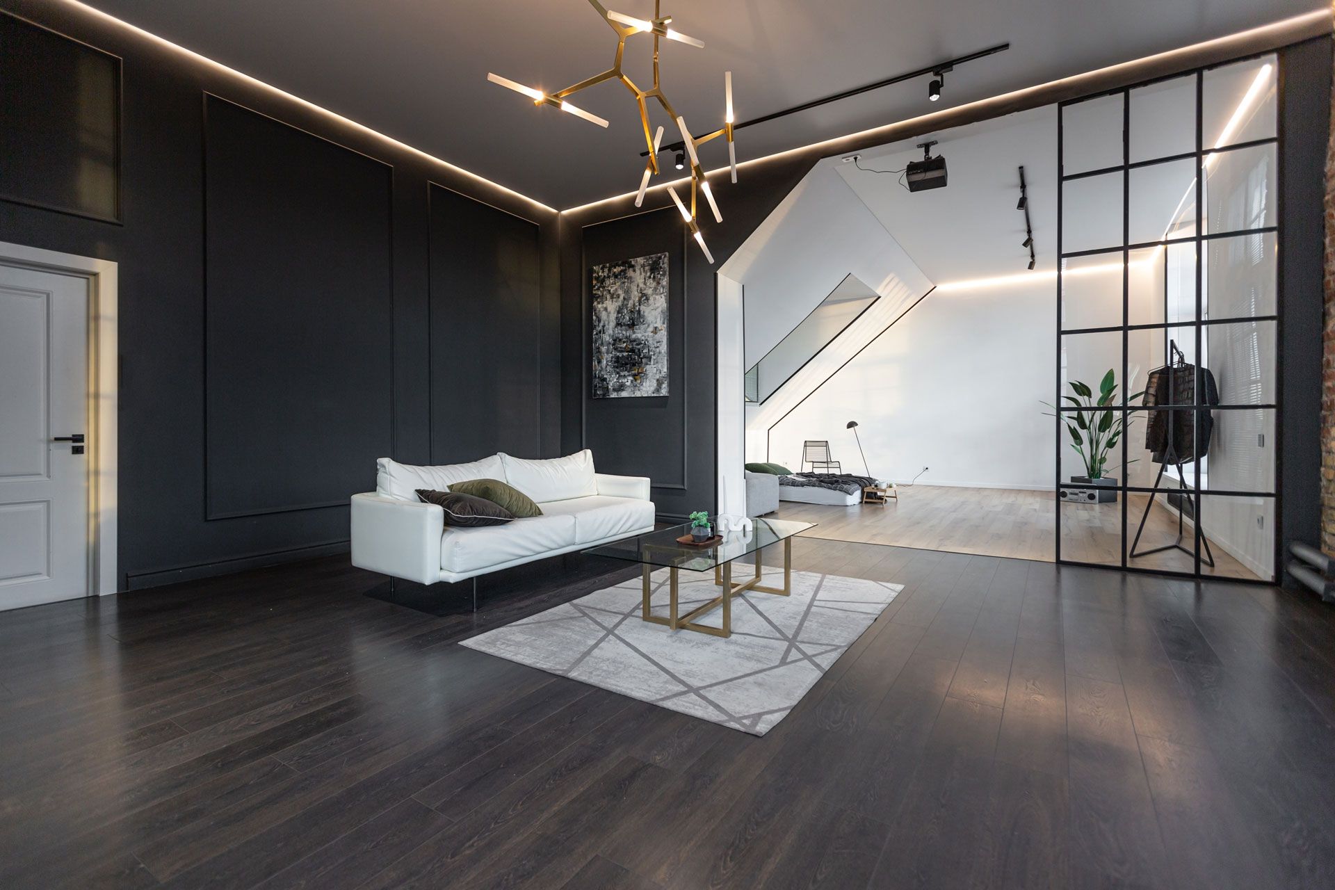 Modern living room with dark walls, white sofa, glass wall, and geometric rug.