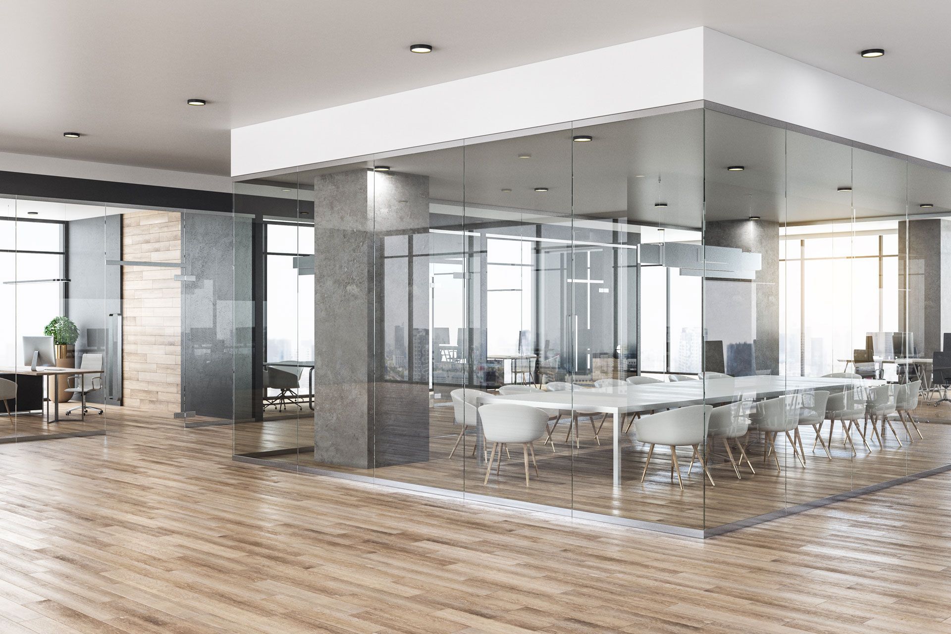 Modern office space with glass-walled conference room, wooden floors, and desks with computers.