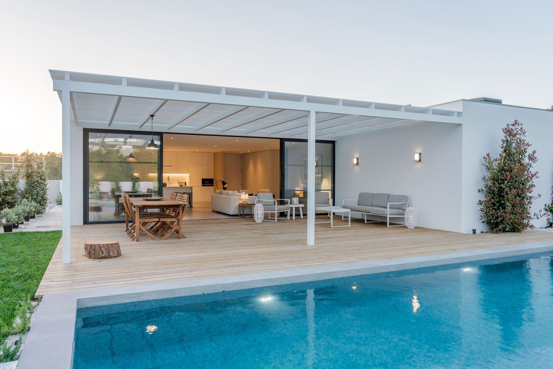 Modern white villa with pool and patio furniture.