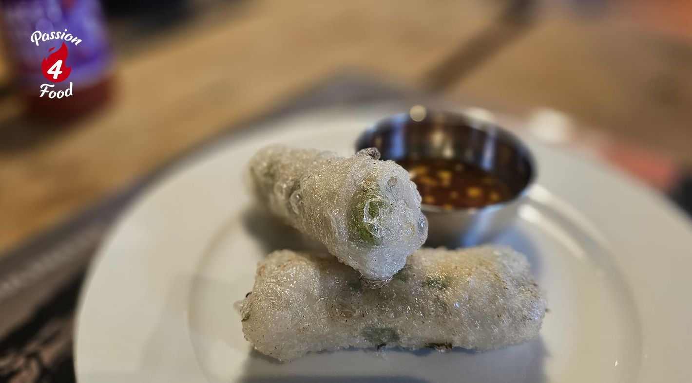 Crispy springrolls met kip, citroengras en frisse nước chấm op wit bord.