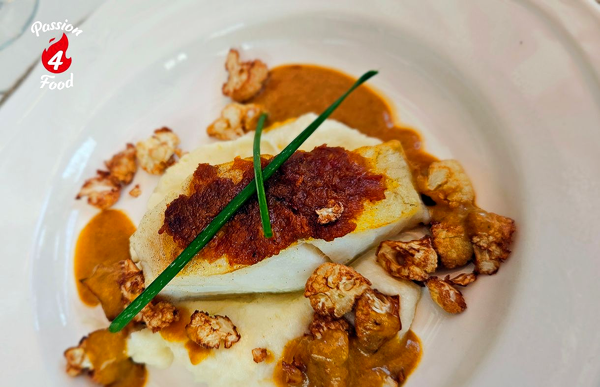 Een prachtig opgemaakt gastronomisch gerecht met witte mousse, rode kruiden, groene bieslook en knapperige garnering.